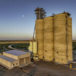 92-foot-tall concrete grain silos at Holcomb Grain Facility with rail loadout tunnel, designed for 80,000 BPH bulk weighing capacity and efficient rail operations.