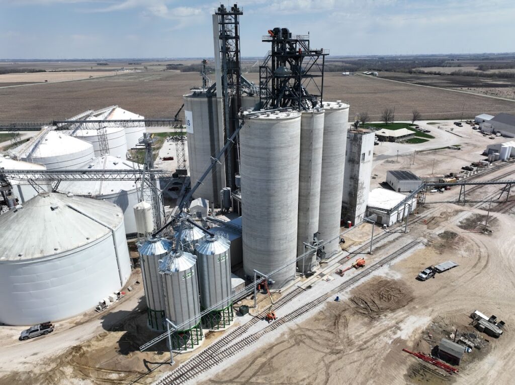 Aerial view of the expanded grain storage facility in Jefferson, Iowa, featuring multiple silos, including a 150-foot-tall slipform concrete structure and two 48-foot diameter grain storage silos, highlighting the agricultural sector's infrastructure development.