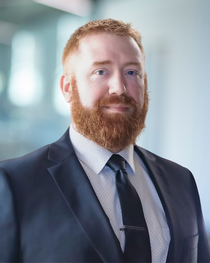 Alex Feaker, BIM Manager and Senior CAD Technician at KC Engineering, wearing a suit and tie, with a well-groomed beard and blue eyes, smiling in a professional setting.