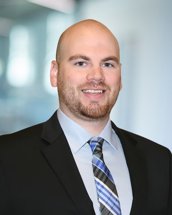 Alex Thompson, Senior CAD Technician at KC Engineering, smiling in professional attire with a plaid tie, against a blurred office background.