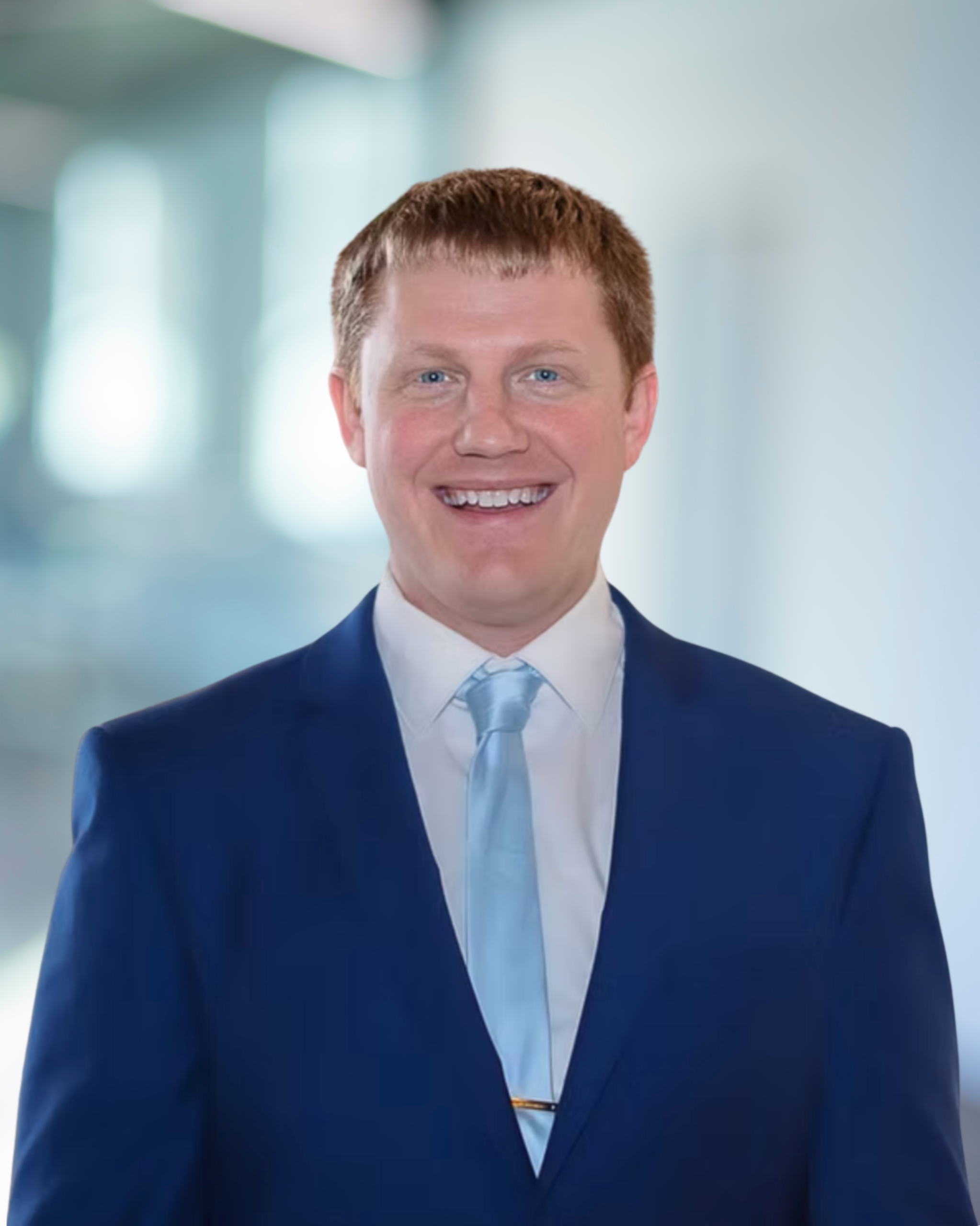 Derek Matthies, Principal and Vice President at KC Engineering, smiling in a blue suit with a light blue tie, against a blurred office background.