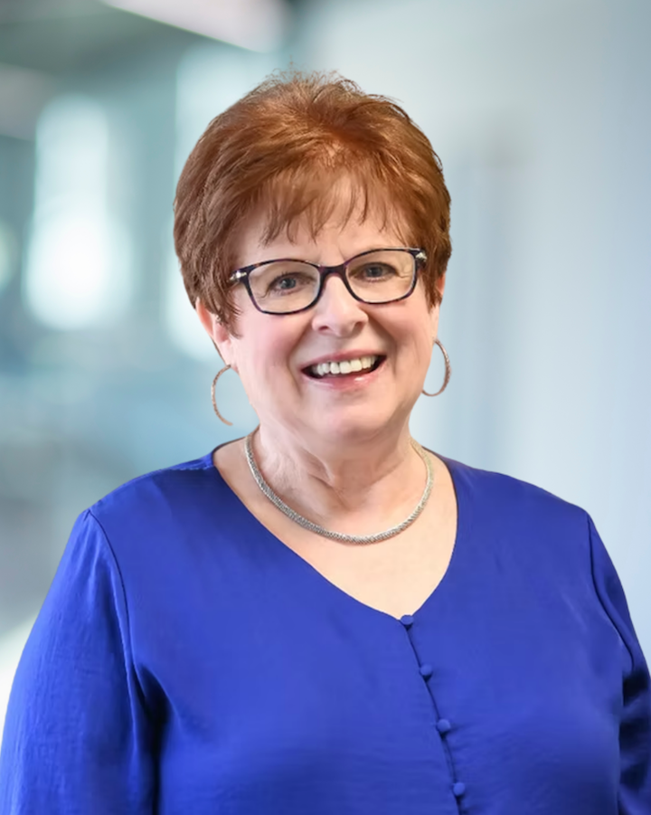 Kathy Allan, Office Manager at KC Engineering, smiling in a blue blouse with a professional background, emphasizing her leadership role and experience in office management and human resources.