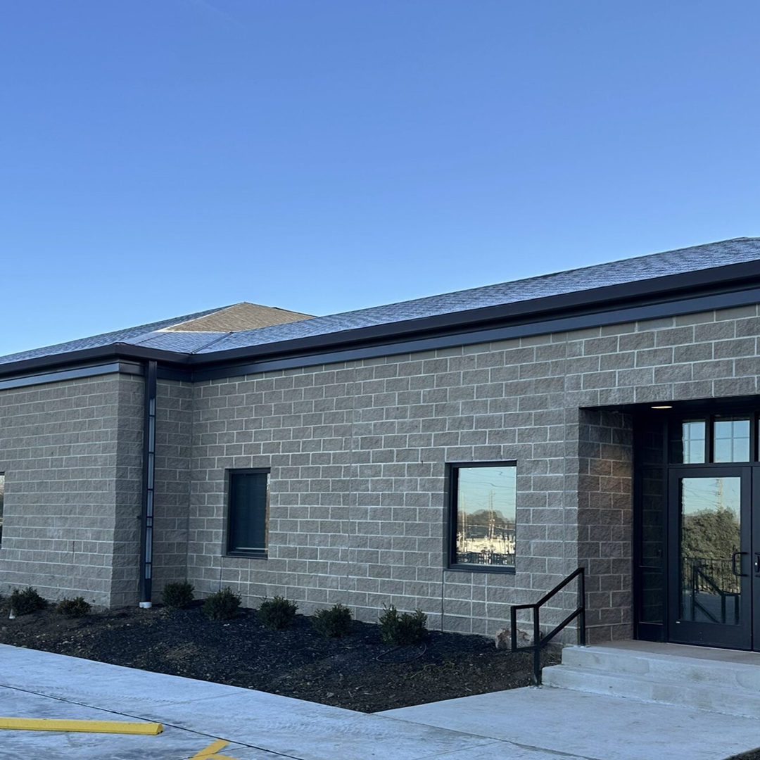 Modern facility exterior featuring gray stone walls, large windows, and a black entry door, illustrating KC Engineering's architectural design capabilities.