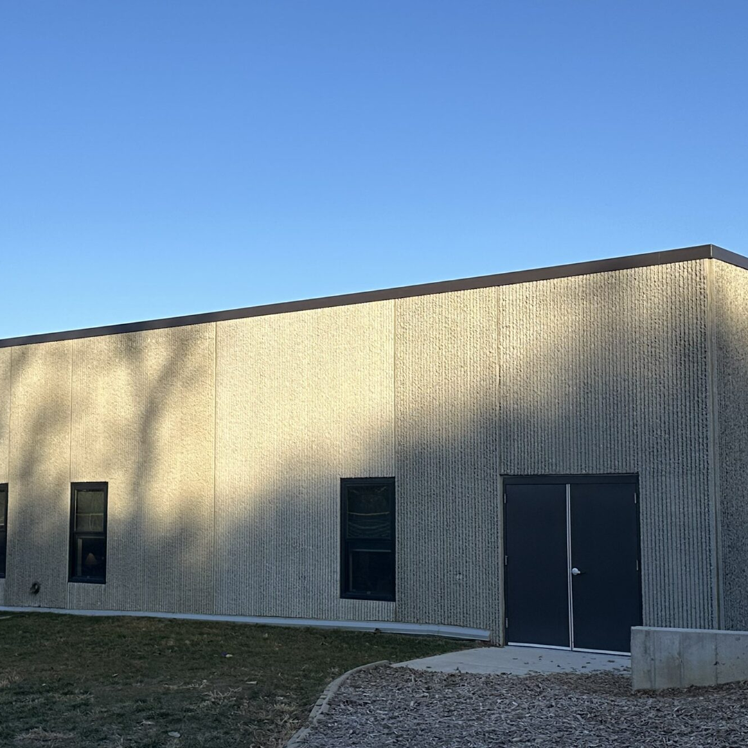 Modern facility exterior with textured concrete wall, windows, and double door, reflecting KC Engineering's architectural design focus on practicality and code compliance.