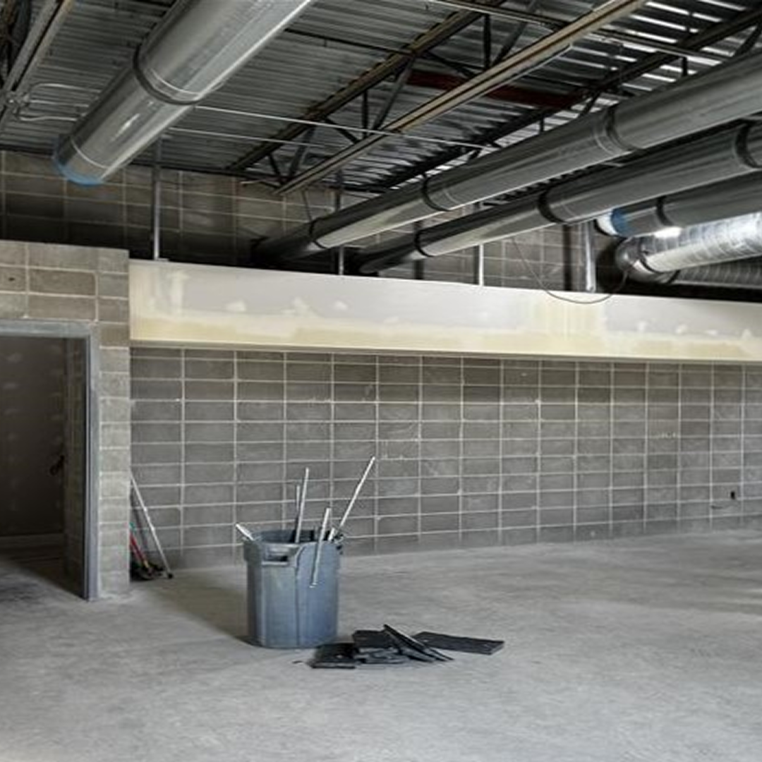 Construction site interior featuring exposed ductwork, concrete block walls, and construction debris, illustrating architectural design and project planning for facility efficiency.