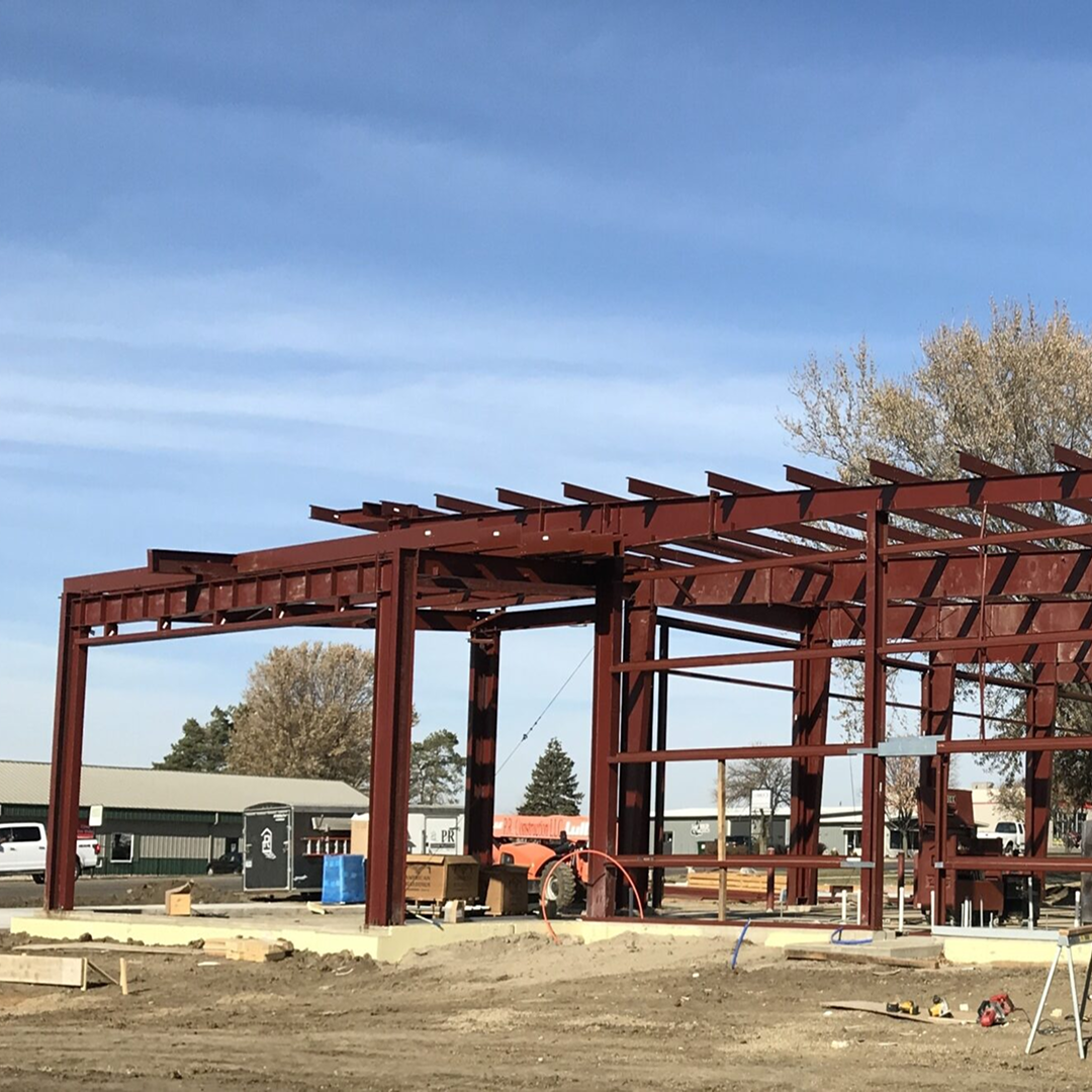 Steel framework of a fire station under construction, showcasing structural components and surrounding site preparation, reflecting KC Engineering's architectural design services for practical and code-compliant facilities.
