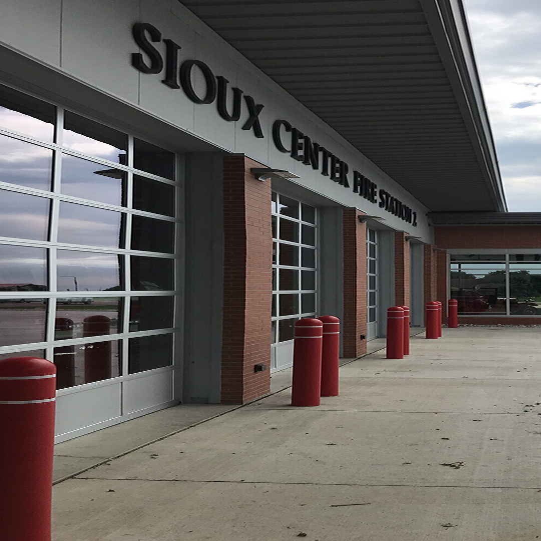 Sioux Center Fire Station exterior with large glass doors, red safety bollards, and modern architectural design, highlighting KC Engineering's focus on practical and code-compliant facility solutions.