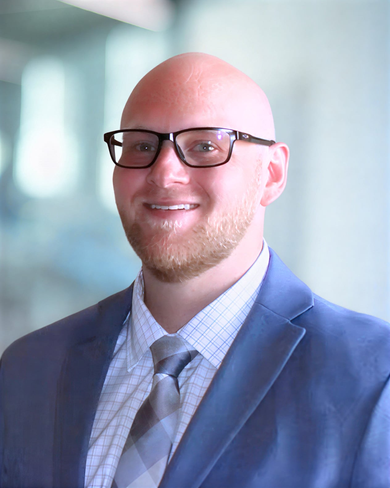 Tanner Fjelstad, Design Architect at KC Engineering, smiling in a professional suit and glasses, showcasing expertise in architecture and Autodesk Revit.