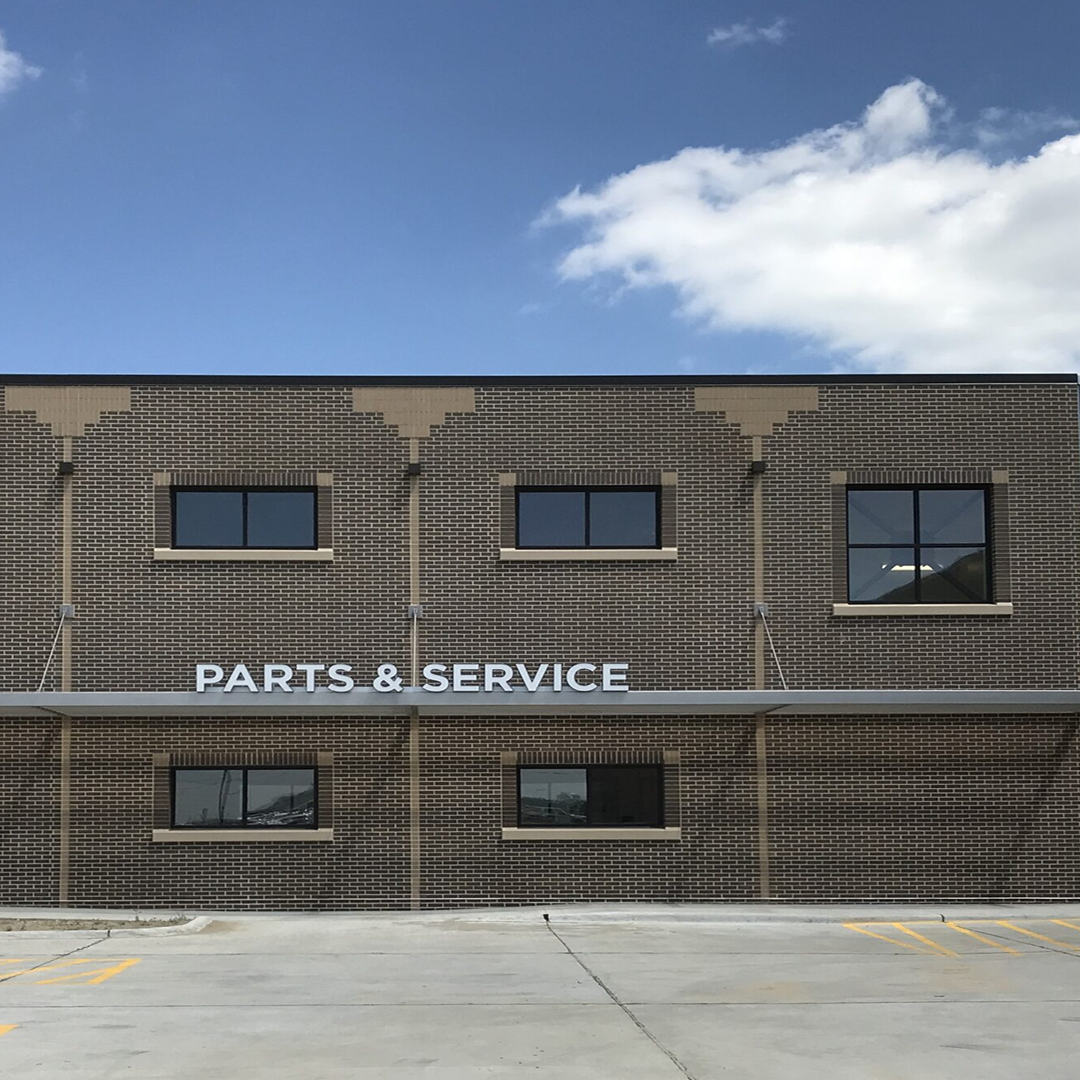 Parts and Service building facade with modern brick design, featuring large windows and clear signage, emphasizing practical architectural solutions for service-oriented facilities.