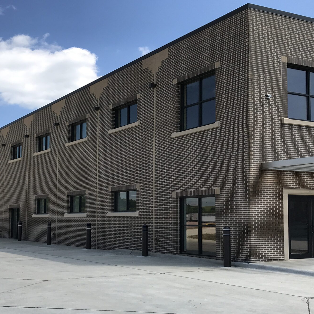 Modern brick building exterior with large windows, featuring architectural detailing and a clear sky backdrop, representing KC Engineering's design capabilities.