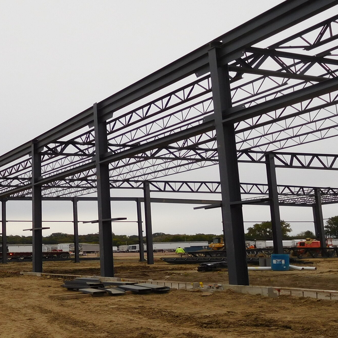 Steel framework of a commercial building under construction, highlighting structural elements and construction equipment on-site, reflecting KC Engineering's focus on practical and code-compliant architectural solutions.