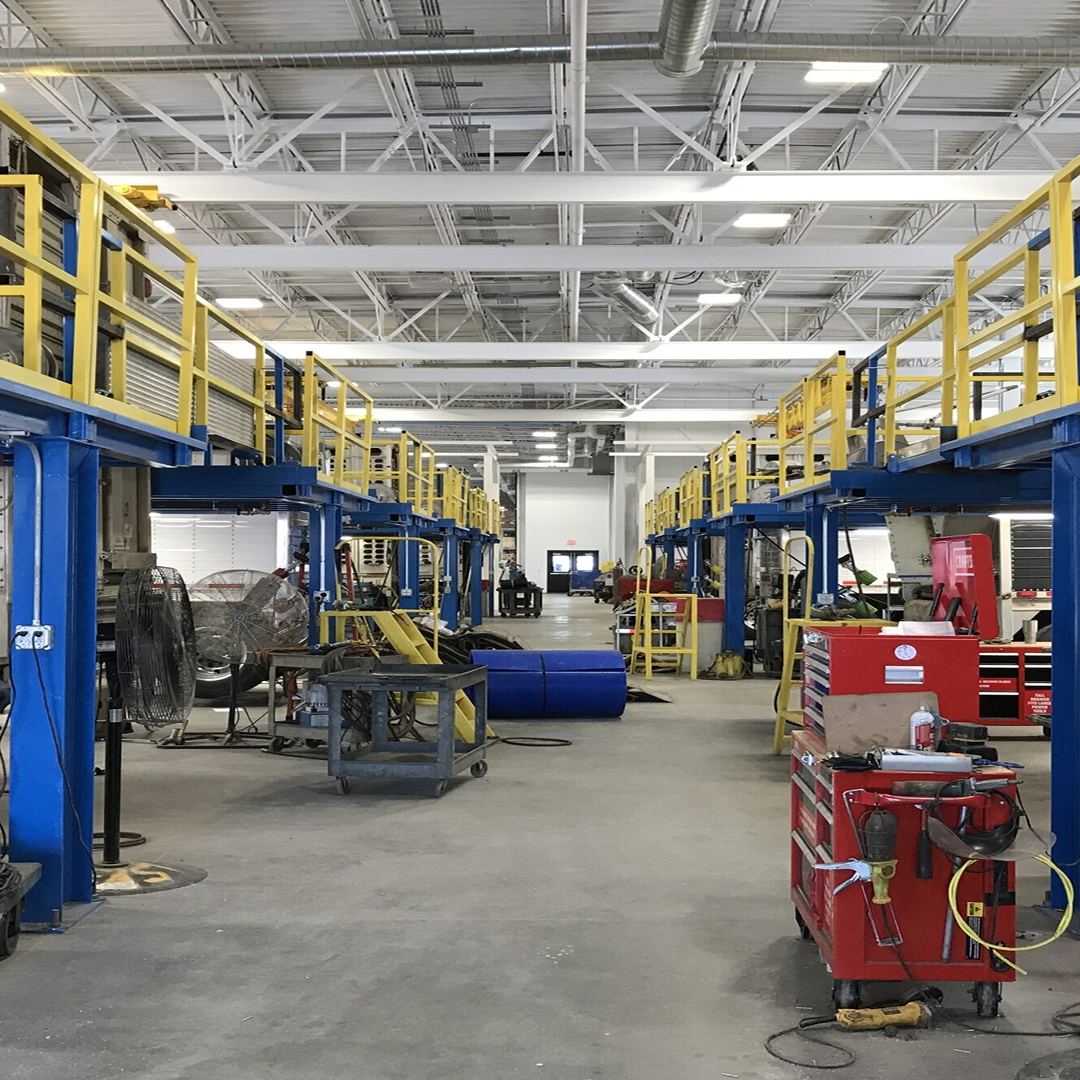 Industrial workshop interior with elevated platforms, blue and yellow structures, tools, and equipment, showcasing a well-organized space for efficient project execution and structural feasibility.