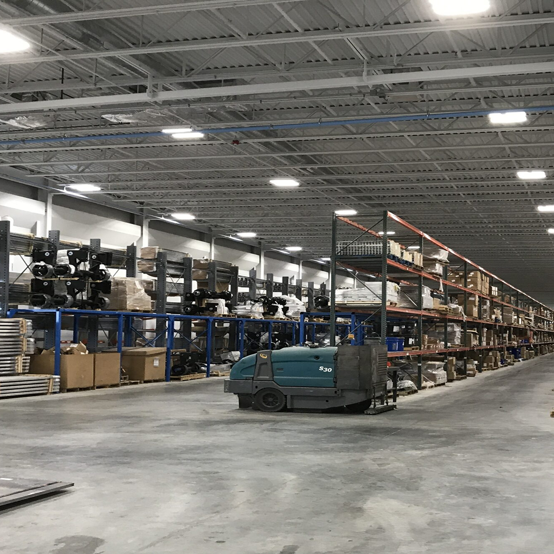 Warehouse interior showcasing organized shelving with various materials and equipment, emphasizing efficient space utilization and project readiness for architectural design services.